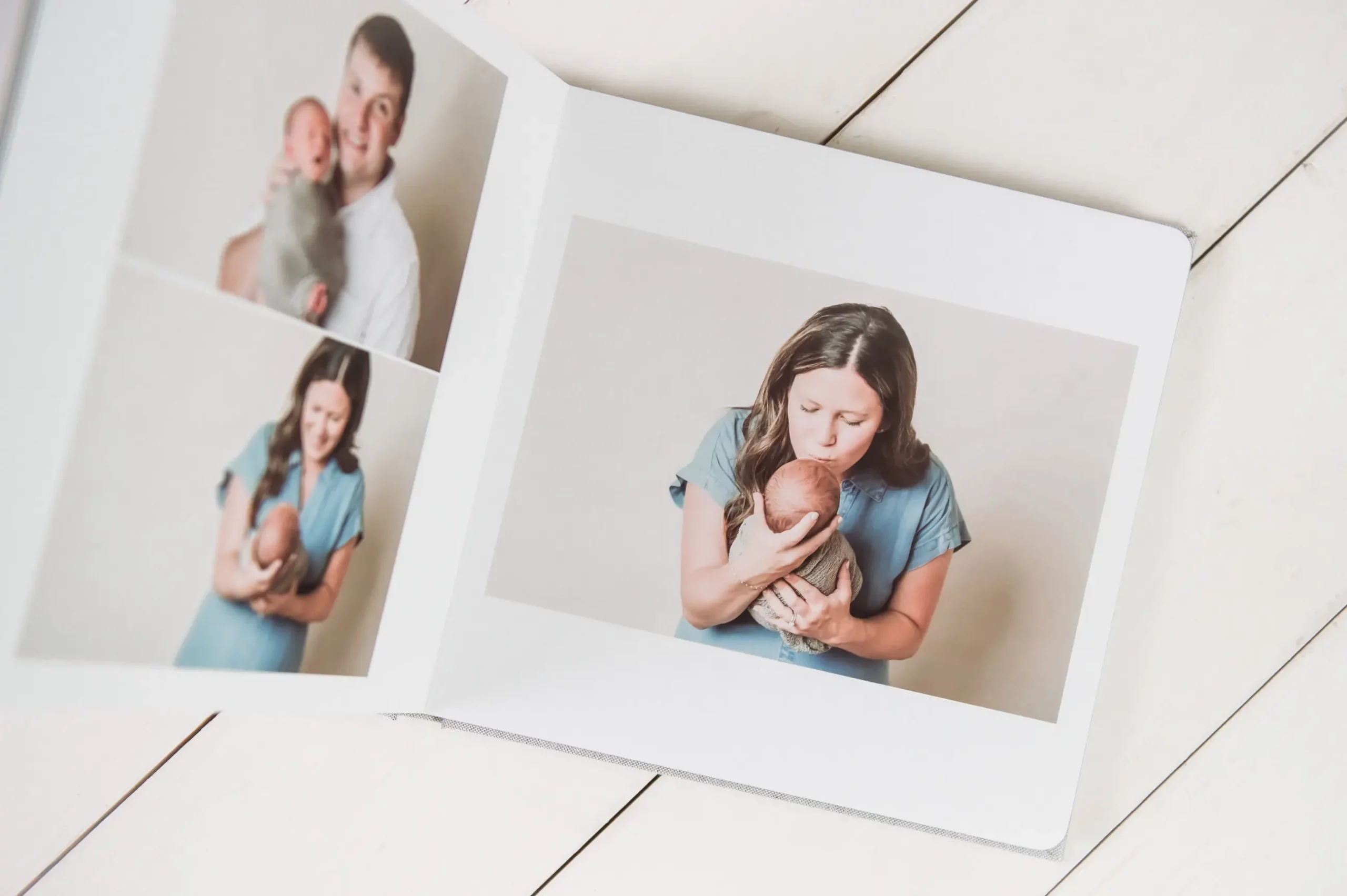 Open photo album on a white wooden surface, showing pictures of a man and woman each lovingly holding and cuddling a