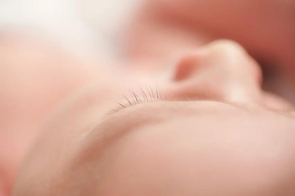 Close-up of a sleeping baby's face, focusing on the delicate eyelashes and smooth skin