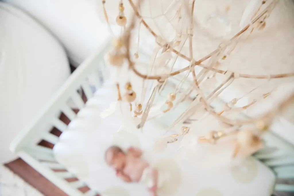 An overhead shot of a baby sleeping in a white crib at home