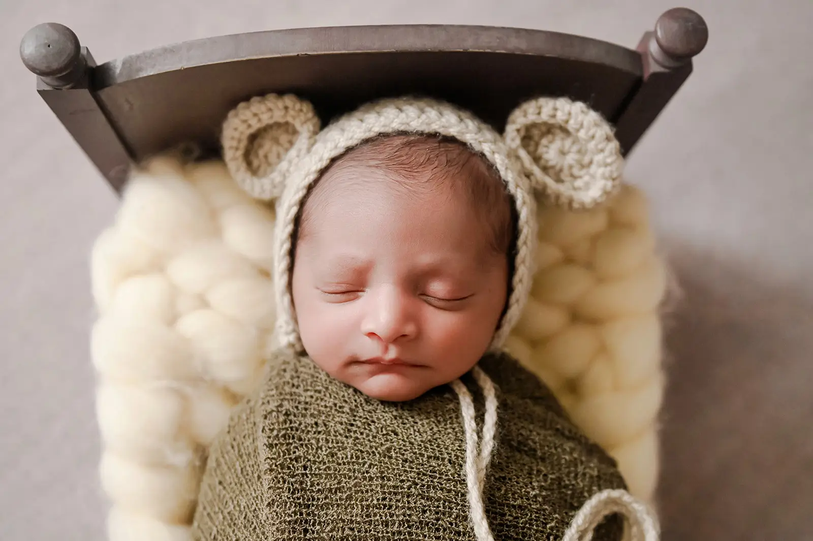 A newborn baby is sleeping peacefully at home, swaddled in a green blanket