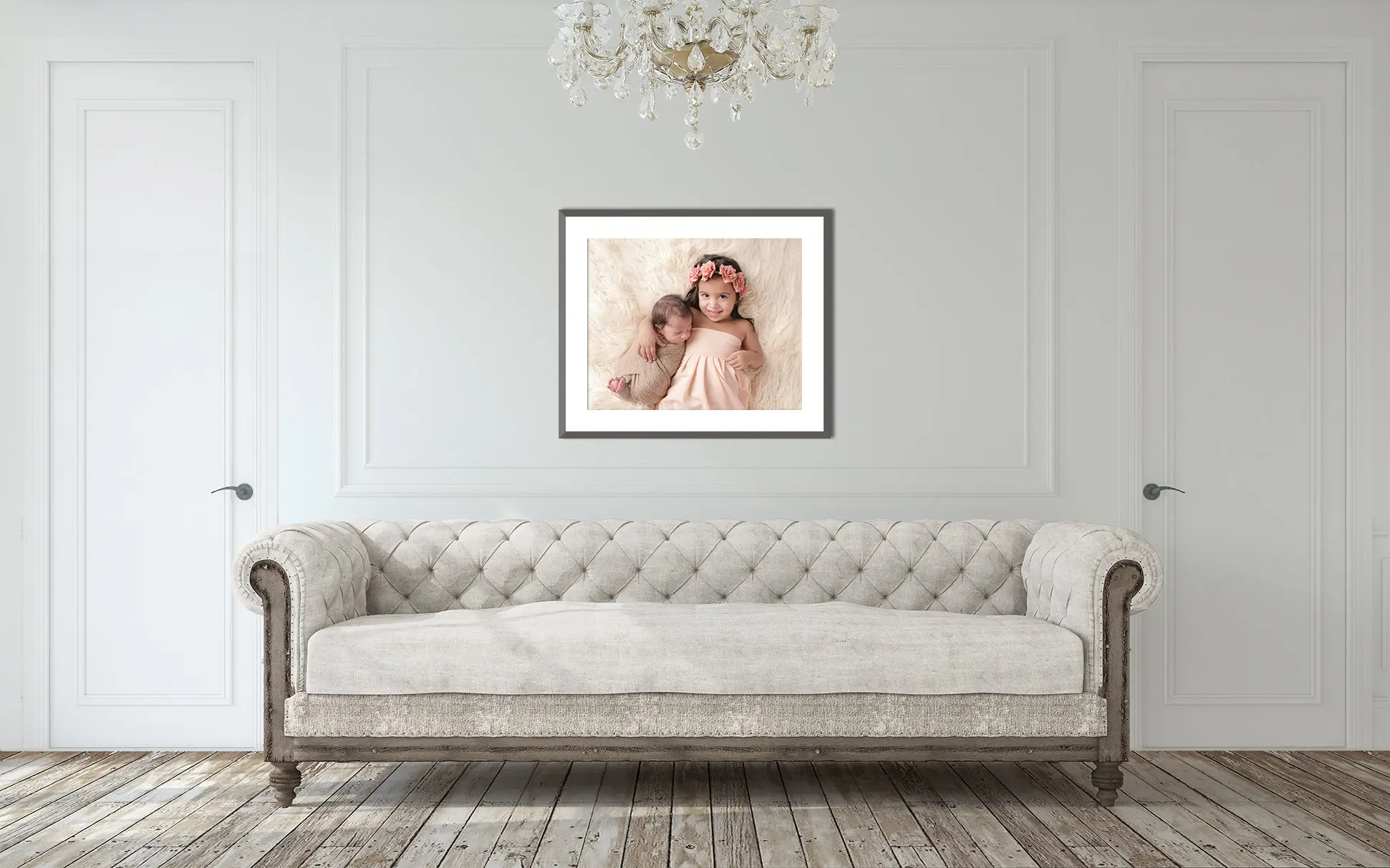 A minimalist living room features a tufted beige sofa with wooden legs against a white wall